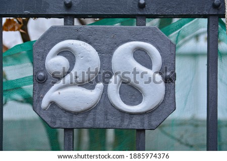 A blue house number plaque, showing the number twenty eight (28)