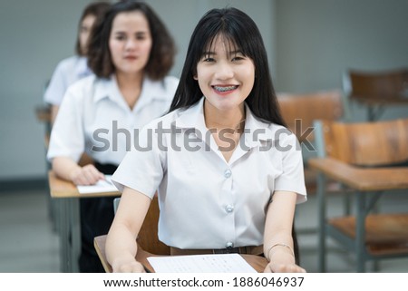 Portrait of cheerful Asian female college students writing and studying in the classroom. Selective fous teenage universty students studying in classroom.