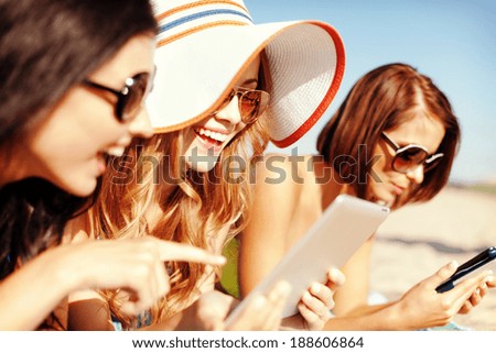 summer holidays, technology and internet concept - girls in bikinis with tablet pc sunbathing on the beach