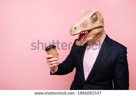 Lizard-headed man holding a recyclable cardboard cup of coffee.