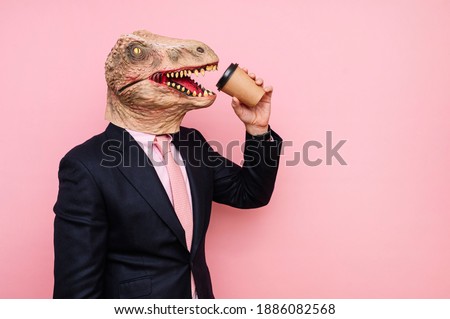 Lizard-headed man holding a recyclable cardboard cup of coffee.