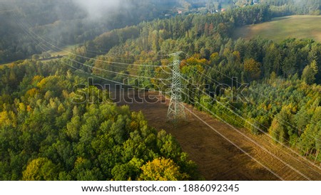 Aerial view of the high voltage power lines and high voltage electric transmission on the terrain surrounded by trees at sunlight Royalty-Free Stock Photo #1886092345
