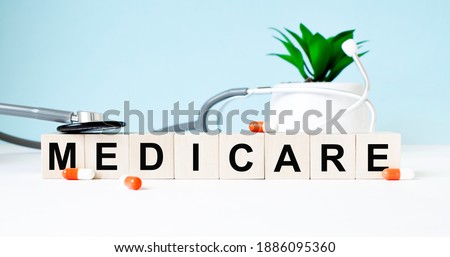 The word MEDICARE is written on wooden cubes near a stethoscope on a wooden background. Medical concept