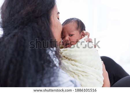 African American mother kissing her newborn baby in blanket. Mom carrying her afro infant child on hands with kindly. family, love, happy and new life concept