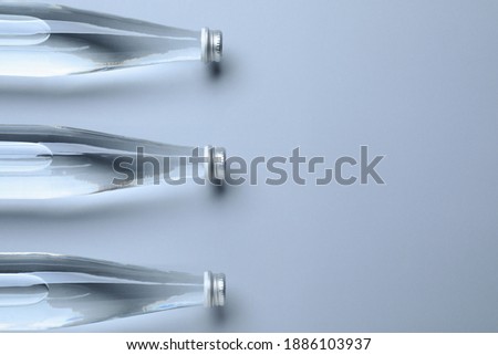 Glass bottles with water on white background, flat lay. Space for text