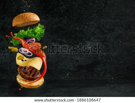 Hamburger with floating ingredients on dark background. Creative still life concept.