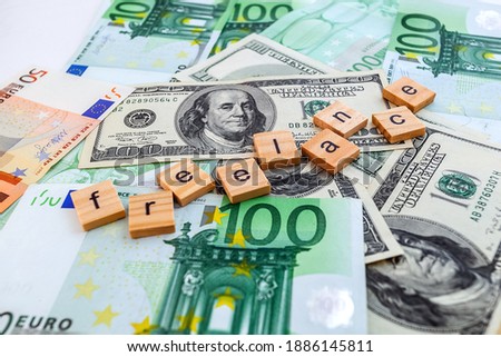 freelance inscription on wooden cubes on the texture of us dollars and euro banknotes