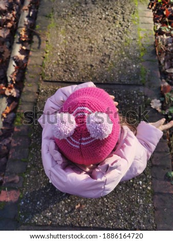Little girl seen from above during a walk into the park. She is dressed for winter time. 