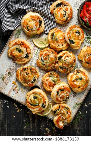 Puff Pastry Pinwheels stuffed with salmon, cheese and spinach served on a board on a black wooden table top view Royalty-Free Stock Photo #1886173159