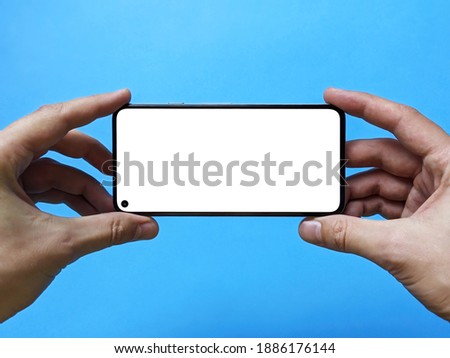 Isolated human two hands holding white mobile smart phone mockup on blue background