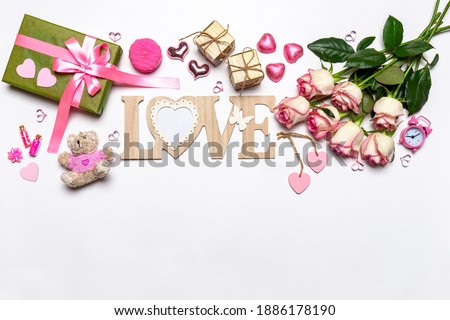 Happy Valentine's day. Roses flowers, LOVE text, hearts, gifts and decorative items in pink pastel colors on white background. Greeting card for Valentine's day, mockup. Flat lay, top view, copy space