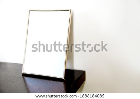 Empty photo frame standing on the wooden table Royalty-Free Stock Photo #1886184085