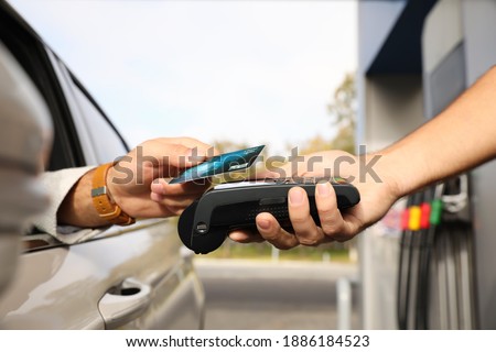 Man sitting in car and paying with credit card at gas station, closeup Royalty-Free Stock Photo #1886184523