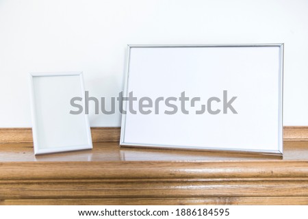 Empty photo frames standing at the wooden fireplace
