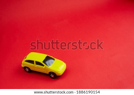 yellow toy car on red background, concept idea of taxi and cargo delivery during quarantine.