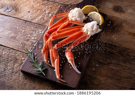 Delicious snow crab leg clusters on a rustic wood table top. Royalty-Free Stock Photo #1886195206