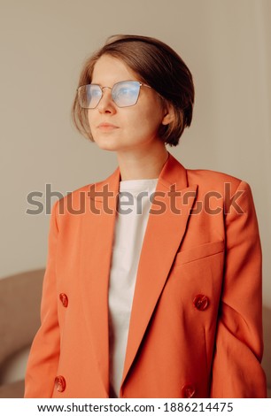 Portrait of happy young woman in coral jacket in studio