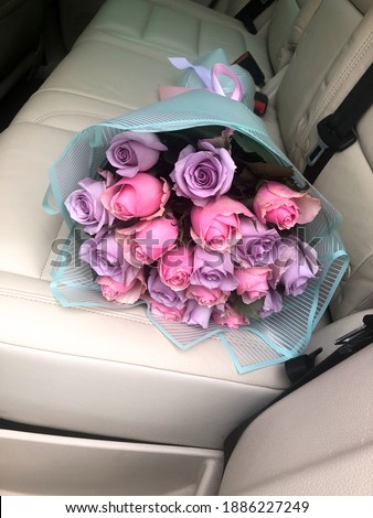  a bouquet of roses in the back seat of a car. lilac and pink flowers. mixed. an armful on a light leather seat. multi-colored, two types