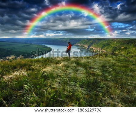 rainbow over the river. woman on a cliff above the canyon