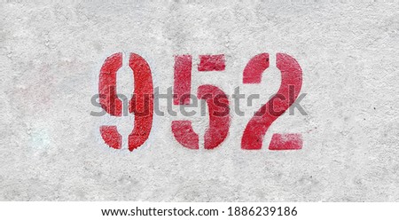 Red Number 952 on the white wall. Spray paint.