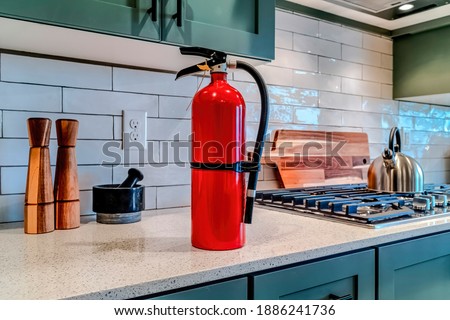 Red fire extinguisher beside cooktop on the countertop inside kitchen of home Royalty-Free Stock Photo #1886241736