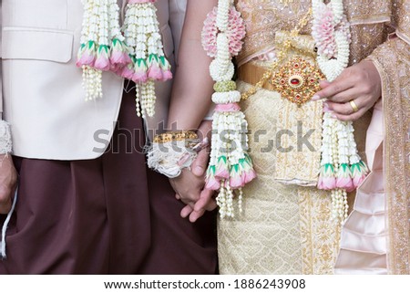 
The bride and groom's hands are held together with love in a traditional Thai wedding ceremony