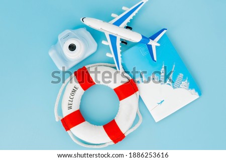 Lifebuoy, passports, camera, model of airplane on blue background. Summer or vacation concept. Copy space.