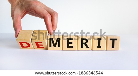 Demerit or merit symbol. Male hand flips wooden cubes and changes words 'demerit' to 'merit'. Beautiful white background, copy space. Business and demerit or merit concept.