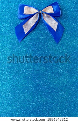 Blue and silver bow on shiny background for text. Copy space