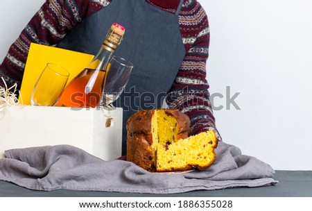 Female hand holding easter panetone italian piece near delivery box with champagne bottle.