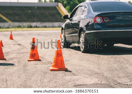 Car and traffic cones, driving school concept. Old orange plastic cone in place for car driving training, extreme driving school at autodrome. Stadium for safe driving training. School training car.