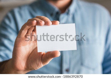 Blank paper business card mockup held by a businessman. Logo and branding design template concept