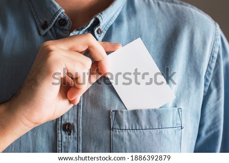 Business card mockup held by a man who puts it in his pocket. Logo and branding design template concept