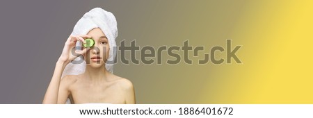 Young girl in studio. Bathroom towel. Cosmetology concept. Skin care product. Female portrait. Cucumber face mask. Fruit scrub. Home peeling. Grey background. Copyspace. Facial lifting treatment