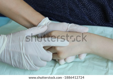 A gloved female hand and patient examination