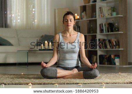 Front view full body portrait of a relaxed woman doing yoga exercise in the night at home with candles Royalty-Free Stock Photo #1886420953
