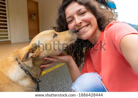 A beautiful brunette girl makes a selfie with her beloved dog. The dog is very happy and excited kisses the girl. Pets and their owners.