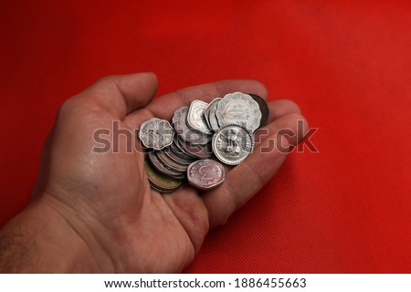 Vintage coins from India in hand on red background