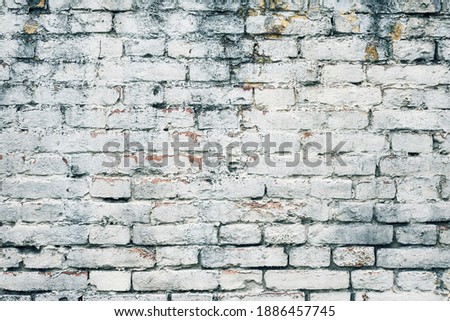 Aged white painted brick wall texture. Old textured grunge wall surface background pattern of masonry. Cracks and black stains.