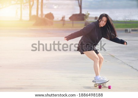 Asian women on skates board outdoors on beautiful summer day. Happy young women play surfskate at park on morning time. Sport activity lifestyle concept Royalty-Free Stock Photo #1886498188
