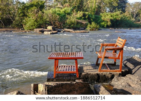 Wooden tables and chairs were placed by the water.                               