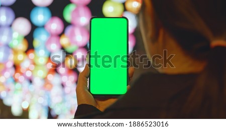 Asian girl see the lanterns and use mobile phone with green screen at night during chinese new year