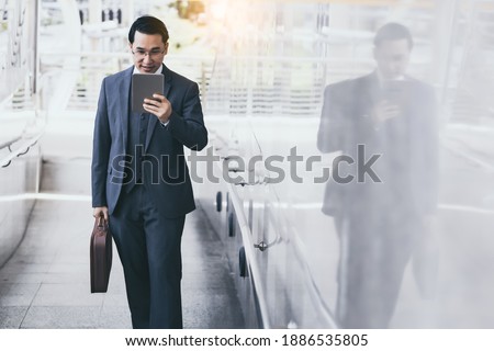 Handsome asian businessman holding digital tablet, wear suit and eyeglasses. Leadership executive business guy get successful of business. Male reading news. Professional businessman portrait