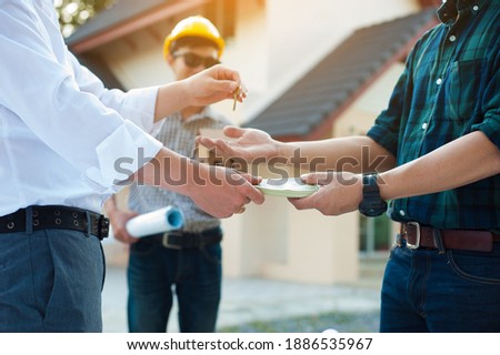 The contractor delivers the keys to the house and receives the payment after completing the construction project. Royalty-Free Stock Photo #1886535967