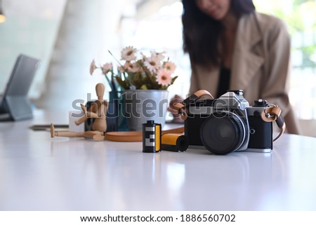 A camera, flower pot and wooden puppet on creative designer or photographer workstation.