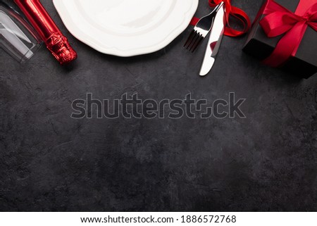 Valentines day with empty plate, champagne, gift box and silverware. Top view flat lay with copy space