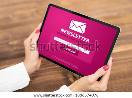 Woman holding tablet with newsletter signup page on screen