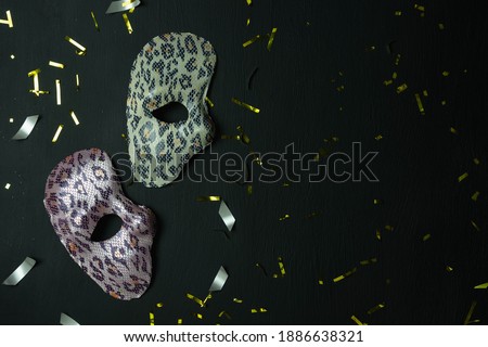 Table top view aerial image of beautiful colorful carnival festival background.Flat lay accessory object the several mask  decor confetti on modern black wooden at home office desk studio.copy space.