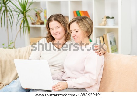 Beautiful young women LGBT lesbian happy couple sitting on sofa  using laptop a computer  in living room at home.