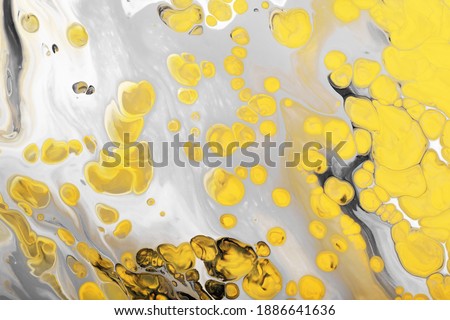 Flow of gray paint with yellow bubbles drops. Marble effect background or texture. Fluid Art. Trending colors of 2021.